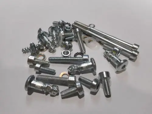 Verschiedene metallene Schrauben, Bolzen und Unterlegscheiben von Remeha auf einem weißen Hintergrund, unordentlich angeordnet.